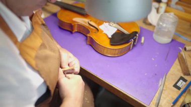 Cropped male unrecognizable male master craftsman using professional tool working on violin bridge while building musical instrument in workshop