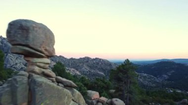 İspanya 'nın Sierra de Guadarrama kentindeki La Pedriza' da akşam saatlerinde gün batımına karşı uzanan dağ zirveleri ve yeşil ormanın nefes kesici manzarası.