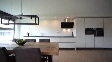 Ahşap masa, tezgahın yanında sandalyeler ve ev yemekhanesi olan güneşli mutfaktaki aletler.