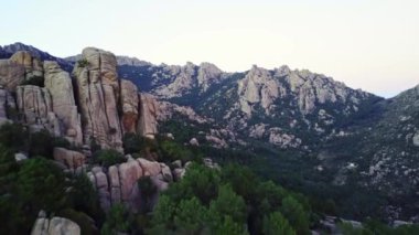 İspanya 'nın Sierra de Guadarrama kentindeki La Pedriza' da akşam saatlerinde gün batımına karşı uzanan dağ zirveleri ve yeşil ormanın nefes kesici manzarası.