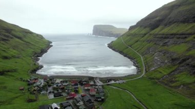 Faroe Adaları 'nda fırtınalı bir günde dalgalanan denizin yanındaki yeşil fiyortta küçük bir yerleşim yerinden.