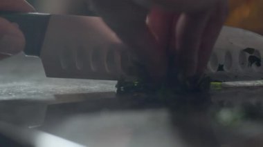 Lokanta mutfağında pizza hazırlarken yeşil maydanozu doğrayan tanınmayan bir erkek şefin yavaş çekim görüntüsü.
