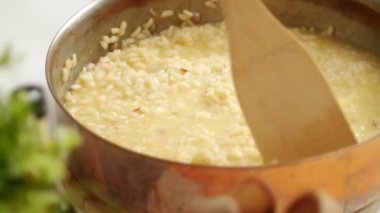 Mutfakta fırında yemek pişirirken tavada ahşap spatulayla acılı risotto karıştıran isimsiz bir şef.