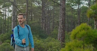 Sırt çantalı ve bastonlu yetişkin bir adamın gündüz vakti yeşil ağaçlıklarda yürüyüş yaparken fotoğrafını çekiyorum.