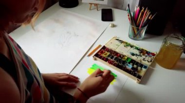 Sulu boyalı atölyesinde resim yapan genç bir kadının görüntüleri..