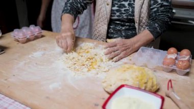 Kimliği belirsiz yaşlı bir kadının hamuru kaşıkla yoğurması ve evde lezzetli İtalyan tortellini pişirmesi.