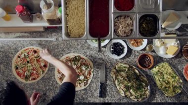 Üst düzey pizza hazırlama süreci mermer tezgahın üzerinde çeşitli sebzeler ve pizza malzemeleriyle birlikte.