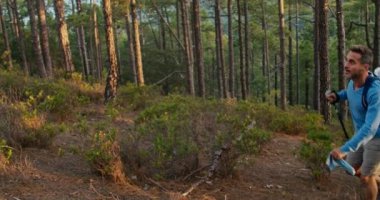 Sırt çantalı ve bastonlu yetişkin bir adamın gündüz vakti yeşil ağaçlıklarda yürüyüş yaparken fotoğrafını çekiyorum.