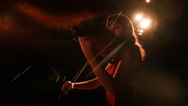 ヴァイオリニストは暗闇の中で演じている 少女はバイオリンを再生します クローズアップ — ストック動画