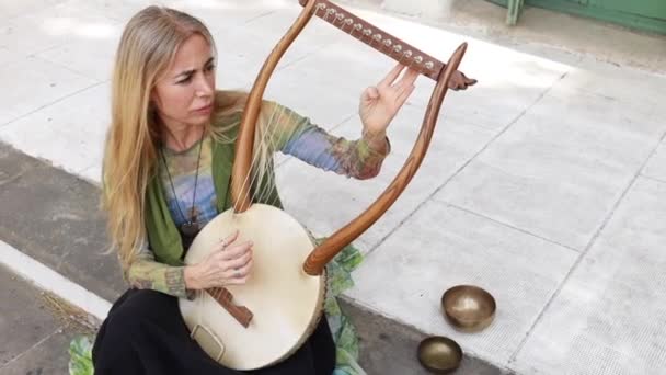 Young Blonde Woman Sitting Playing Lyre — Stock Video