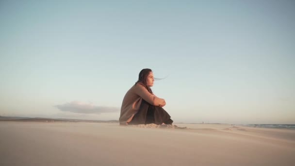 在黎凡特 坐在沙滩上 抱着膝盖 一边欣赏着阳光灿烂的日子 一边心平气和地沉思着的女性 — 图库视频影像