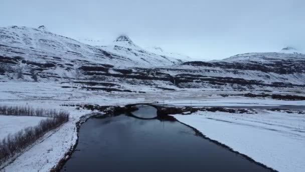 冰岛灰蒙蒙的冬日桥过雪山山脉附近平静湖泊的图片 — 图库视频影像