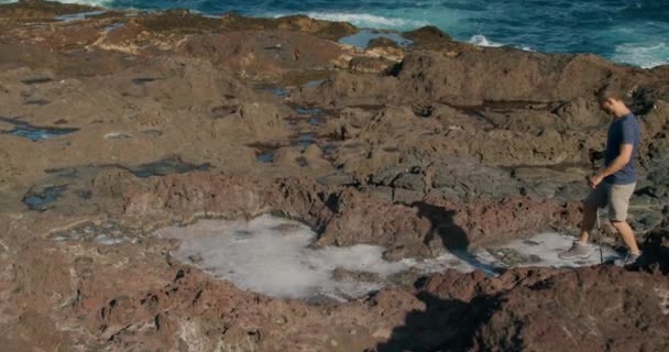 テネリフェ島 カナリア諸島 スペインの波海近くの岩の海で歩くスティックを持つ男性の高角度追跡ショット — ストック動画