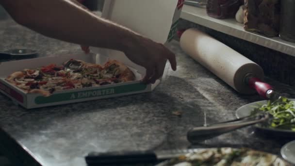 栽培されていない認識できないオスのピザイオーロは ピザ屋で働いている間に配達のためにカートンボックスに焼きたてのおいしいピザを入れて — ストック動画