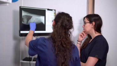 Üniformalı isimsiz kadın gaziler klinikteki evcil hayvan vücudunun radyografik görüntüsüne bakarken konuşuyor.