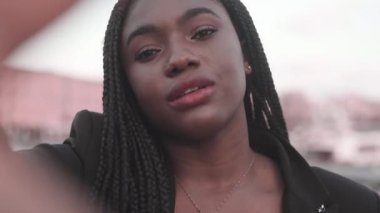 Siyah takım elbiseli genç bir Afro-Amerikan kadının eliyle yüzünü örterek kameraya baktığı görüntüler. 