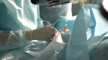 Lateks eldivenli ve üniformalı cerrahların klinikte ameliyat yapmalarının yan görüntüsü.