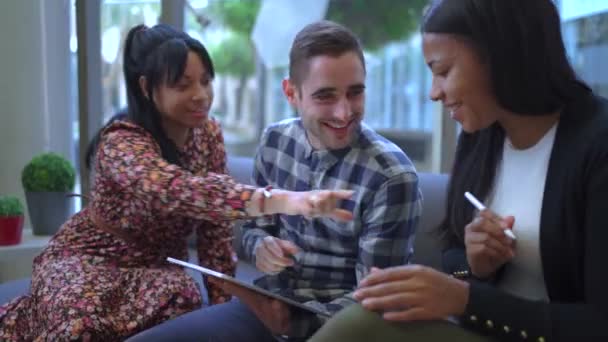 사무실의 레크리에이션 영역에서 태블릿에 연필을 소파에 다인종 동료의 긍정적인 — 비디오