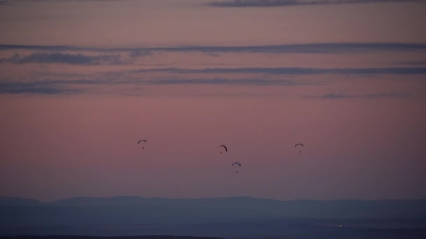 遥不可及的降落伞在阴沉沉的落日的天空中飘扬的轮廓 — 图库视频影像