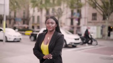 Siyah takım elbiseli genç Afrikalı Amerikalı bir kadının sokakta yürüdüğü görüntüler.  
