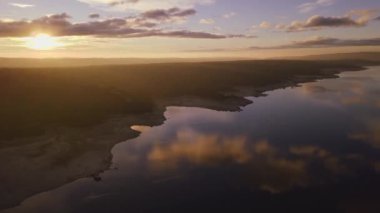 Gün batımında bulutlu gökyüzünün altında göl manzarası