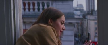 Londra 'nın şehir caddesini akıllı telefonlu bir pencereden videoya çeken kadın.