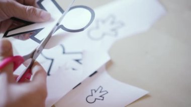 Yukarıdan gelen makas gri zeminde Nisan 1 için farklı kağıt siluetleri kesiyor