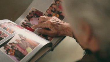 Yukarıdan gelen kadın koltukta oturuyor ve fotoğraf albümünden başka birine aile fotoğraflarını gösteriyor.