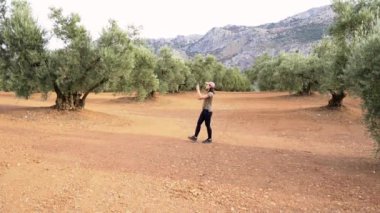 Tam bir kadın gezgin vücudu zeytinlikte gezinirken kırsal kesimdeki akıllı telefondan yeşil ağaçların fotoğraflarını çekiyor.