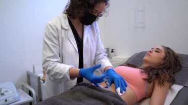 Profesyonel güzellik uzmanı güzellik kliniğinde selülit tedavisi sırasında kadına iğne yapıyor.