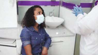 Tıbbi eldivenli erkek doktor Afro-Amerikan kadınını hastanede aşılıyor.