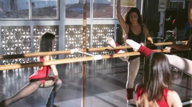 Genç kızlar ayna önünde parlak bir stüdyoda dans ediyorlar. Yavaş çekim, yumuşak hareket. Modern dans kavramı