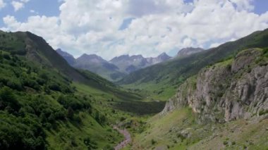 Güneşli bir günde Pireneler 'deki yeşil vadiden akan sığ kayalık dere manzarası.