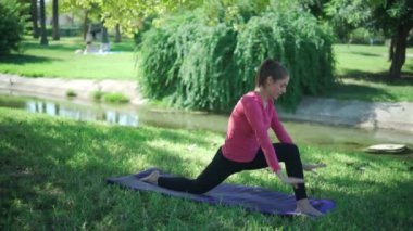 Aktif giyimli gerçek zamanlı sportif kadın vücudu parkta pilates eğitimi sırasında hafif atlama ve kalas çalışması yapıyor.