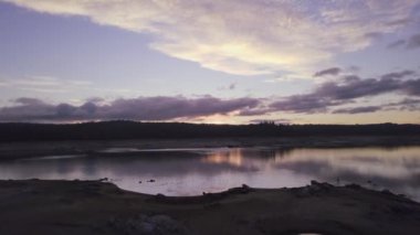 Gün batımında bulutlu gökyüzünün altında göl manzarası