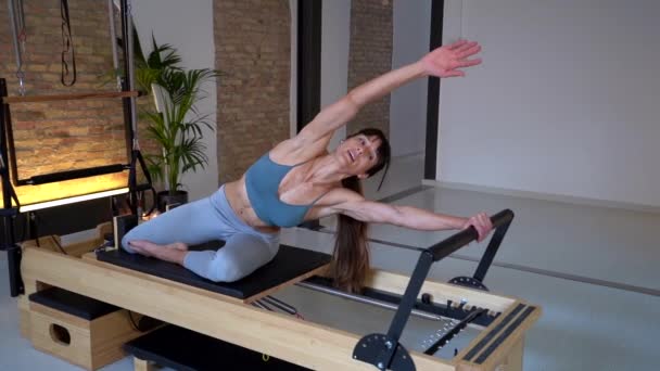 Flexible Elegante Hembra Haciendo Ejercicios Reformador Pilates Mientras Estira Las — Vídeos de Stock