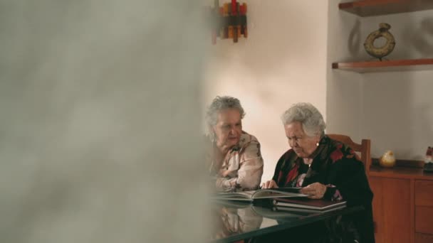 Idősebb Nővérek Képeket Nézegetnek Fotóalbumon Beszélgetnek Emlékekről Miközben Otthon Ülnek — Stock videók