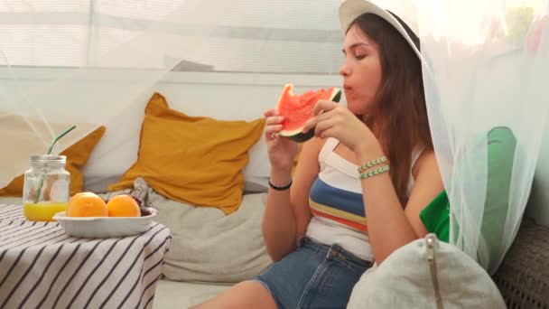 穿着夏装的无忧无虑的年轻女性一边吃成熟的多汁西瓜 一边在后院帐篷里避寒 — 图库视频影像