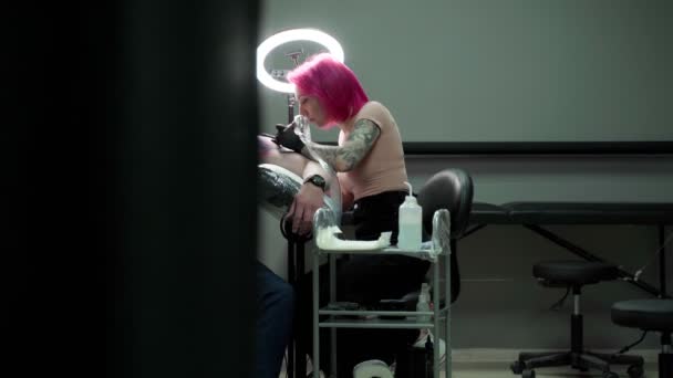 现代纹身沙龙在顾客肩头纹身时 使用专业纹身机制作手套粉色头发纹身大师 — 图库视频影像