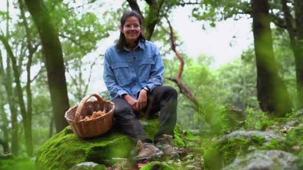 森林里坐在苔藓卵石上的快乐微笑的女菌丝学家 — 图库视频影像