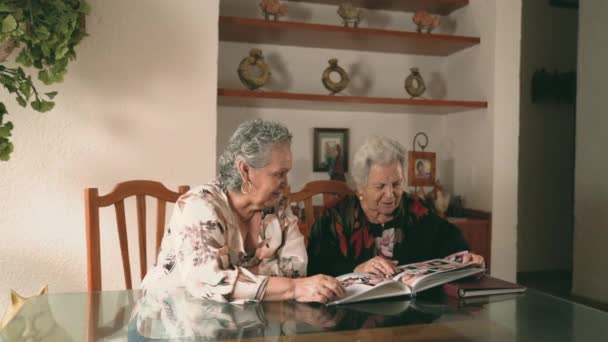 Äldre Systrar Inspekterar Bilder Fotoalbum Och Diskuterar Minnen När Sitter — Stockvideo