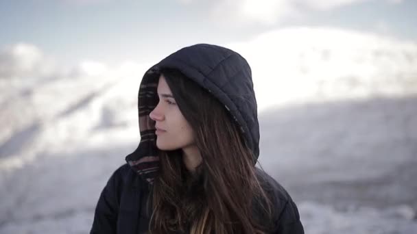 在阳光明媚的冬天 年轻温文尔雅的女旅行家站在雪山边看着相机 — 图库视频影像