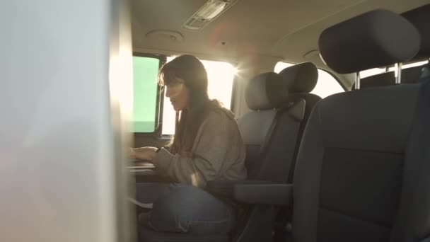 公路旅行期间在面包车上工作时浏览笔记本电脑的女性旅行者侧视图 — 图库视频影像