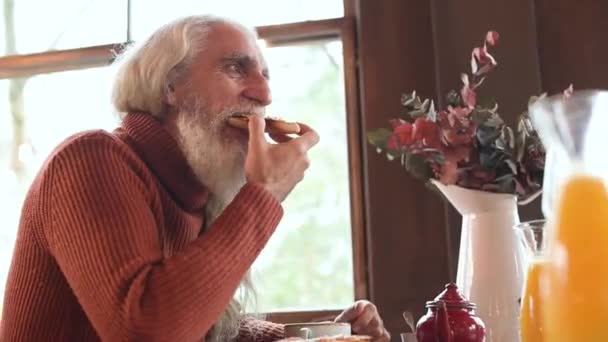 中老年白发大胡子男子早餐享用美味面包西红柿的侧视图 — 图库视频影像
