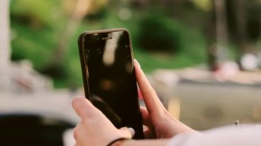 Genç ve güzel bir kadın yeşil bir parkta akıllı telefonuyla selfie çekiyor.