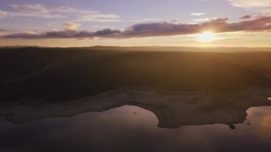 Gün batımında bulutlu gökyüzünün altında göl manzarası