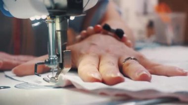 Atölyede dikiş diken genç bir kadın.