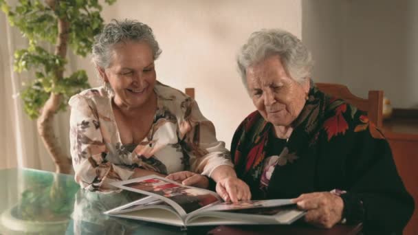 Ηλικιωμένες Αδελφές Επιθεώρηση Εικόνες Στο Άλμπουμ Φωτογραφιών Και Συζητώντας Τις — Αρχείο Βίντεο