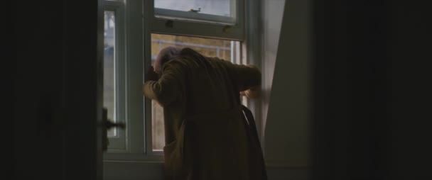 茶色のコートの女性が窓の自由から出て行く — ストック動画