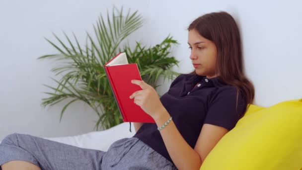 清晨光着脚的年轻女子坐在床上看书 — 图库视频影像